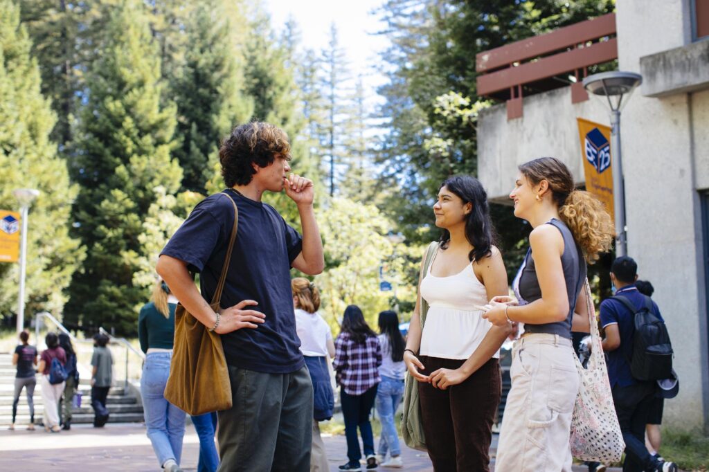 Students talking after class outside with trees in the background.