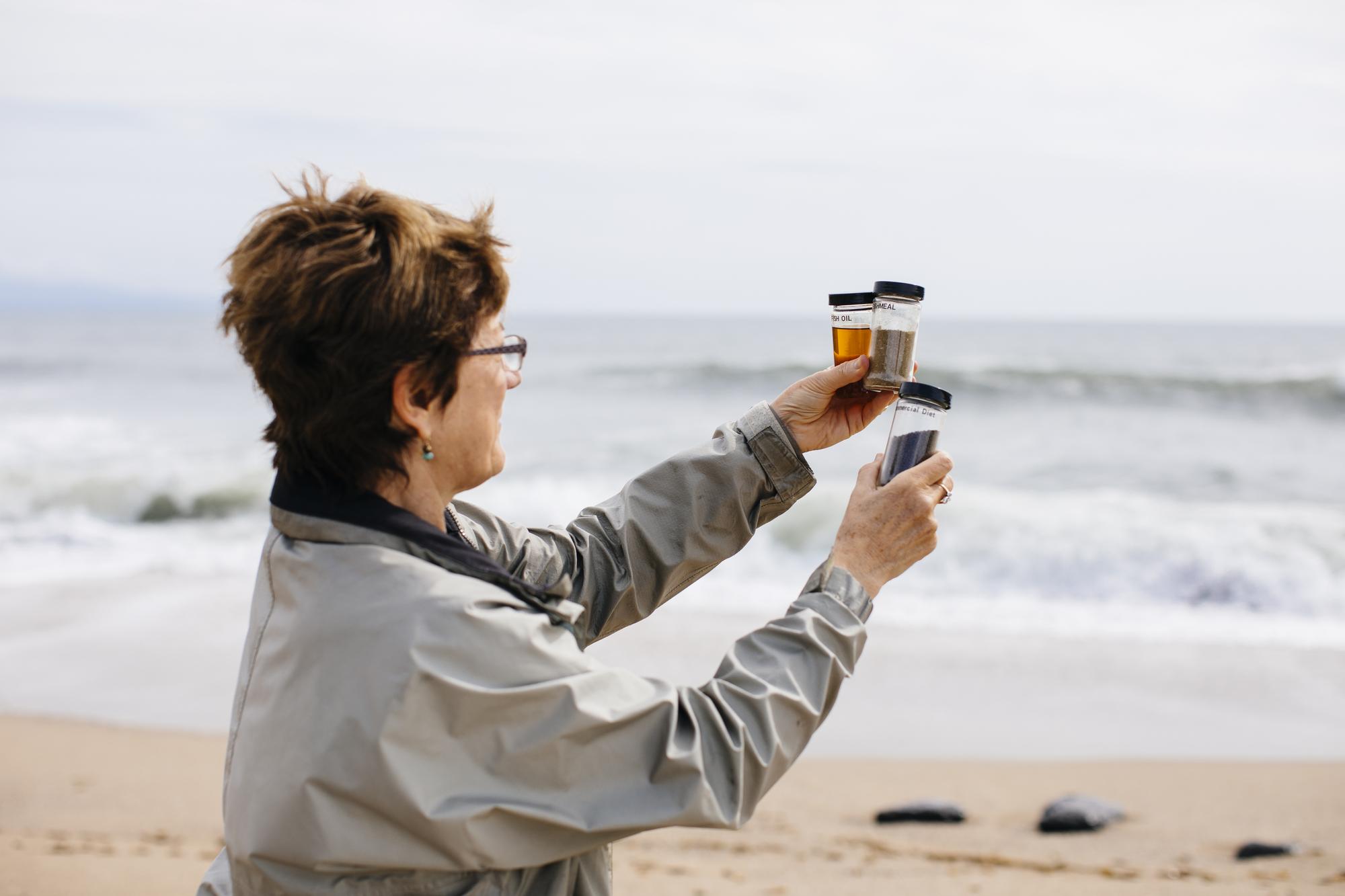 researcher on the beach holding up water specimens.