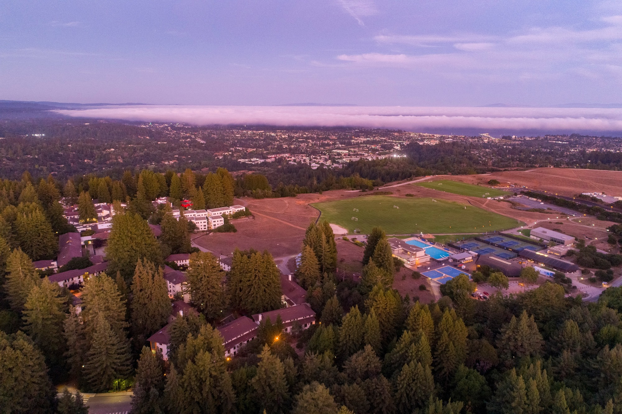 Aerial shot of campus at sunset with Santa Cruz city in  the background.