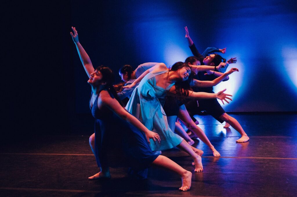 dancers on stage in a line with a back light.