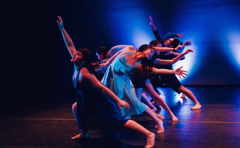 dancers on stage in a line with a back light.
