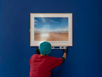 Person hanging a photo is a gallery.
