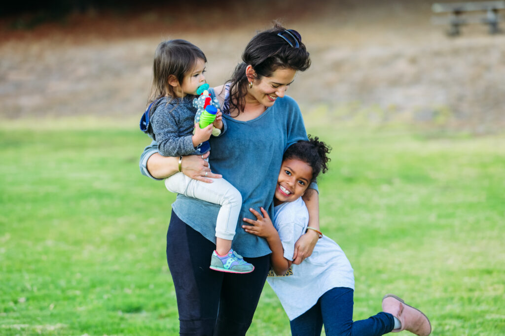 A mother with her two kids playing on grassy field at UCSC.