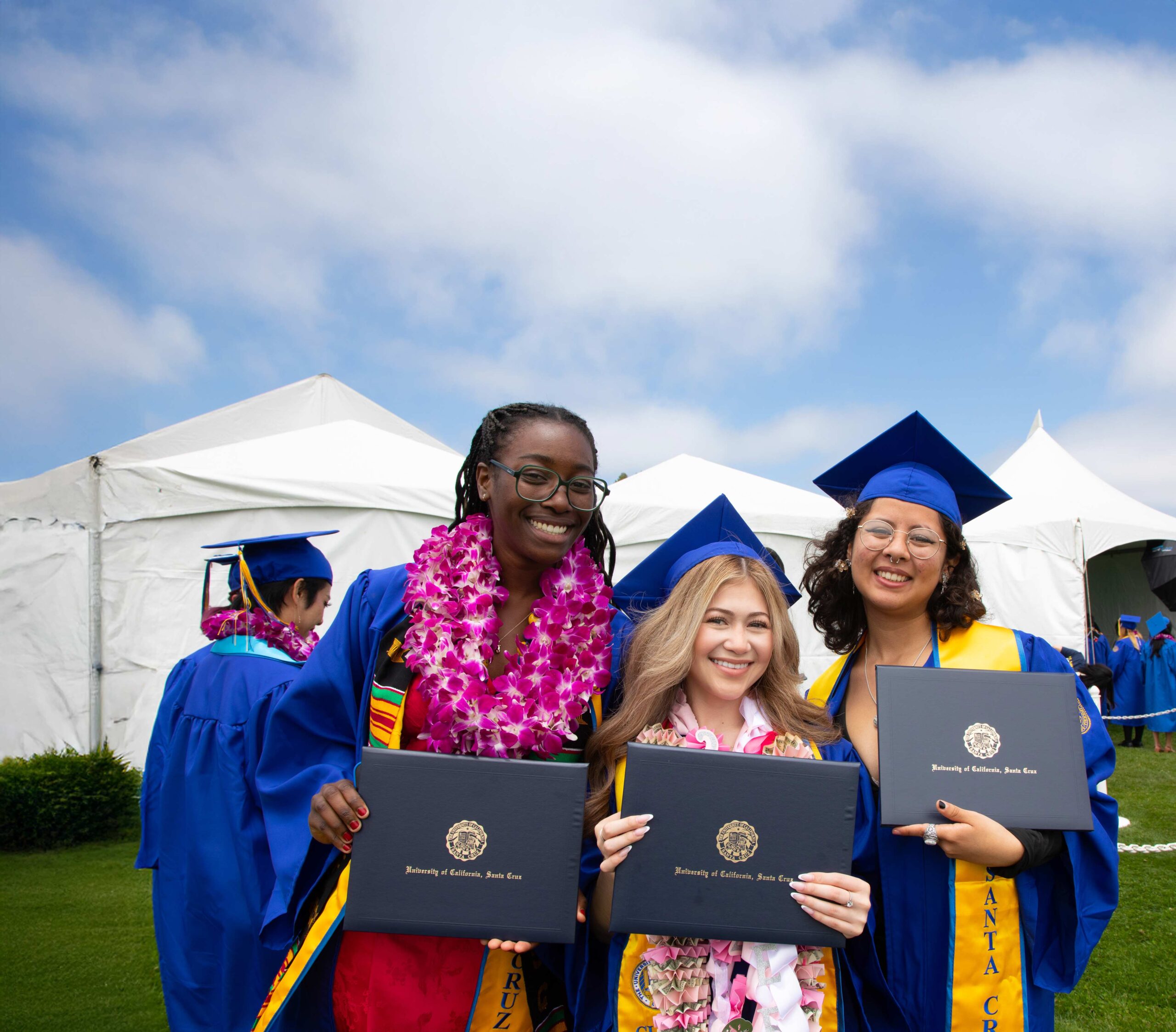 Graduates showing their diploma covers after commencement.