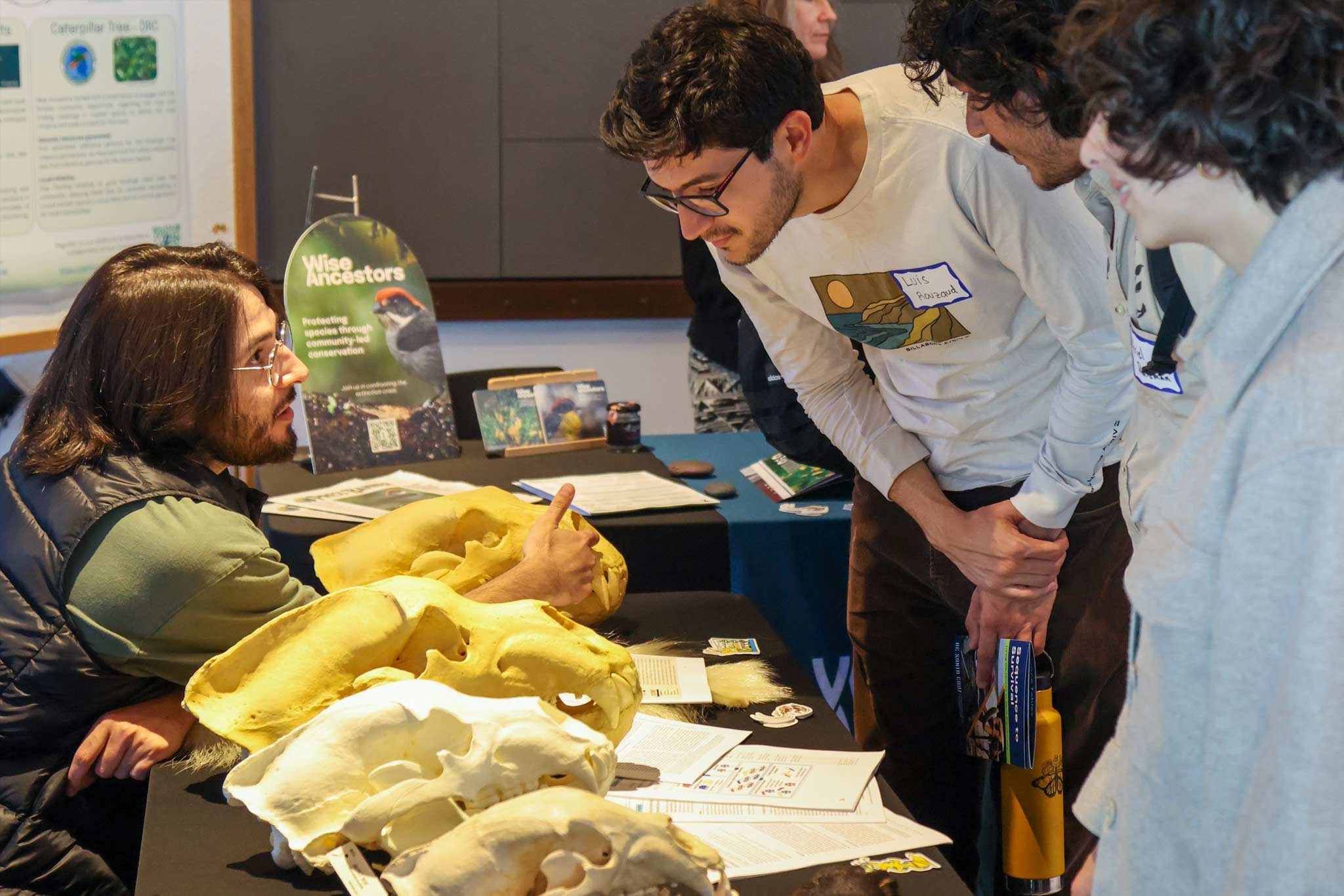 A man talking to students visiting a table that is displaying bear skulls.