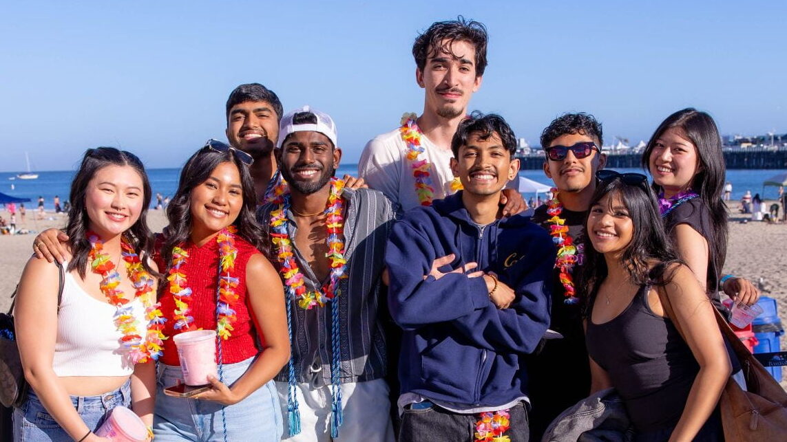 A group of alumni posing together outdoors near the ocean.