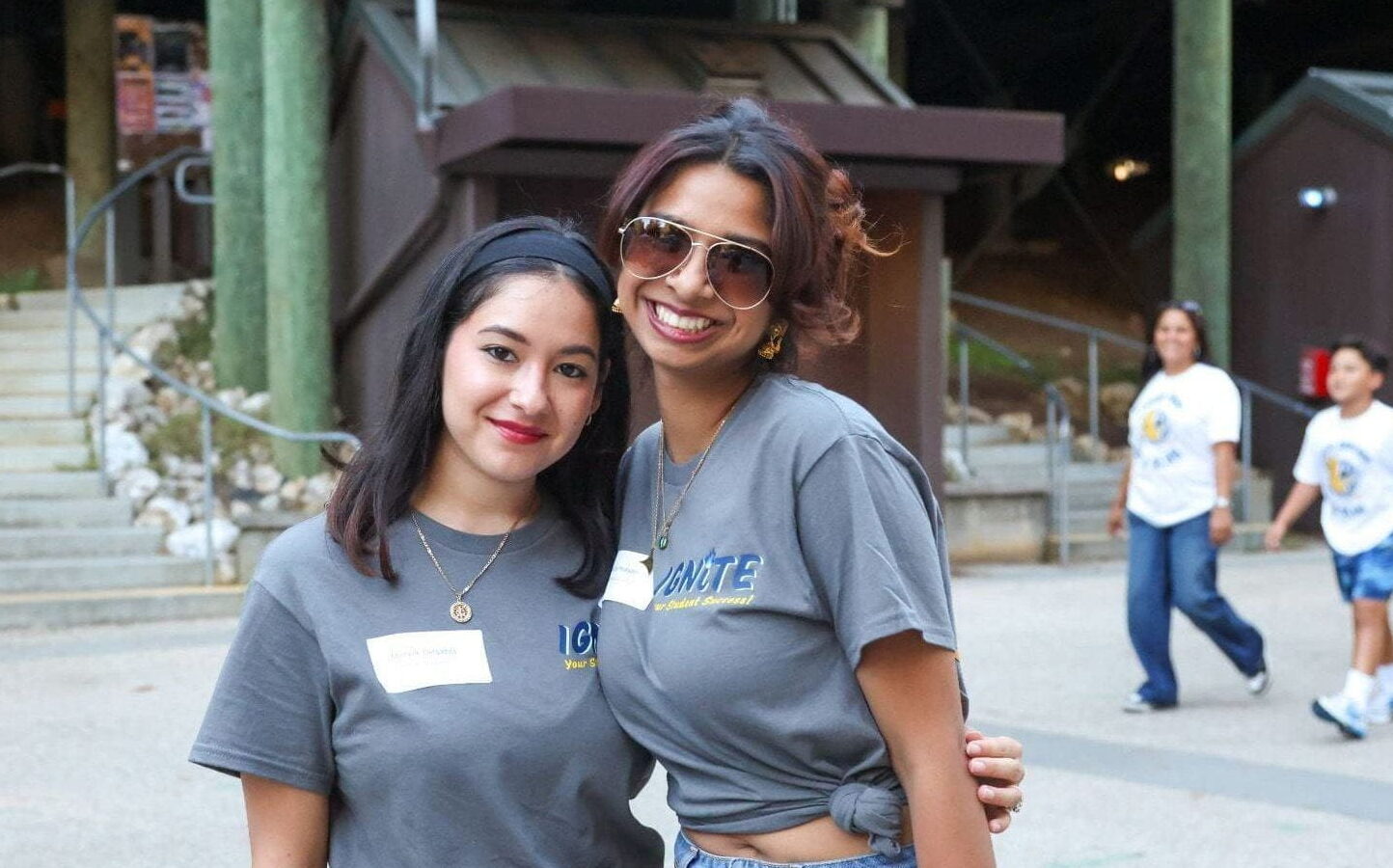 Two students smiling together outdoors near campus buildings.